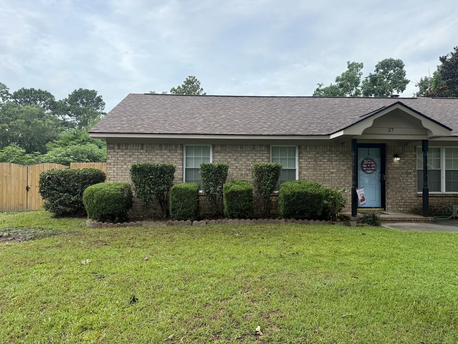 Neatly rounded and trimmed shrubs along the front of a brick home