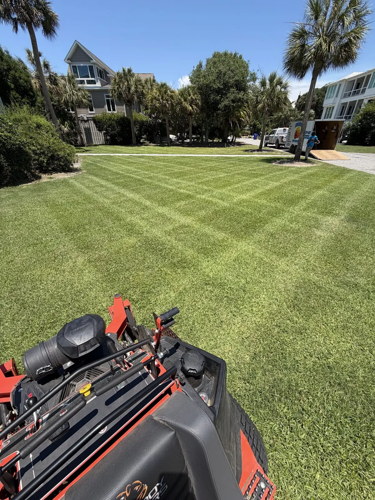 The ShoreCut crew and trailer on a palm lined barrier island street beside a crosshatched lawn