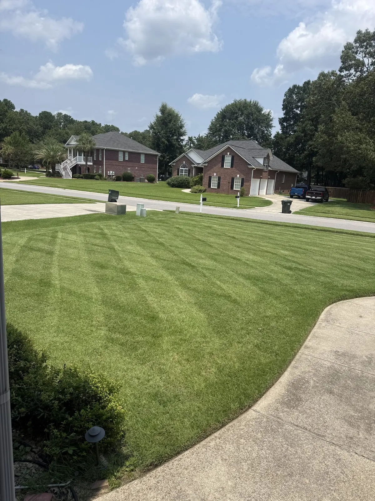 A striped front lawn beside a brick home