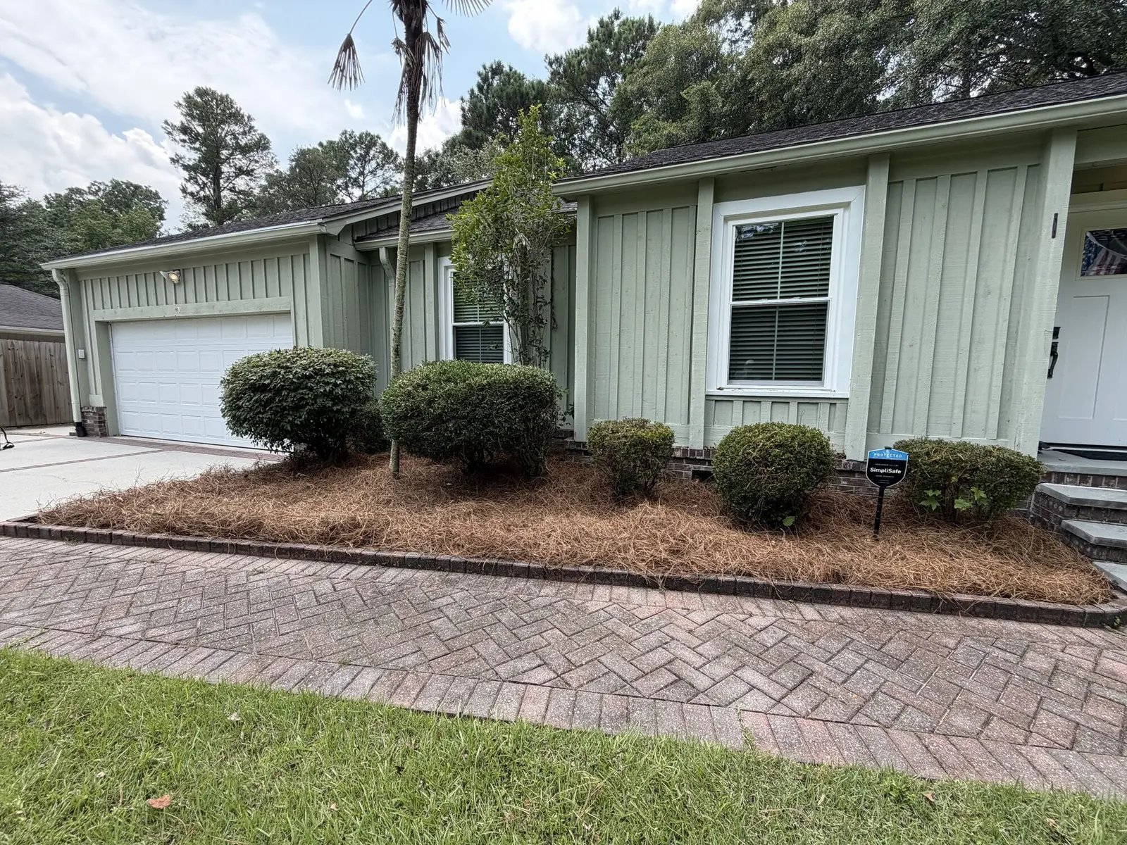 Fresh pine straw mulch laid along a planting bed in front of a house