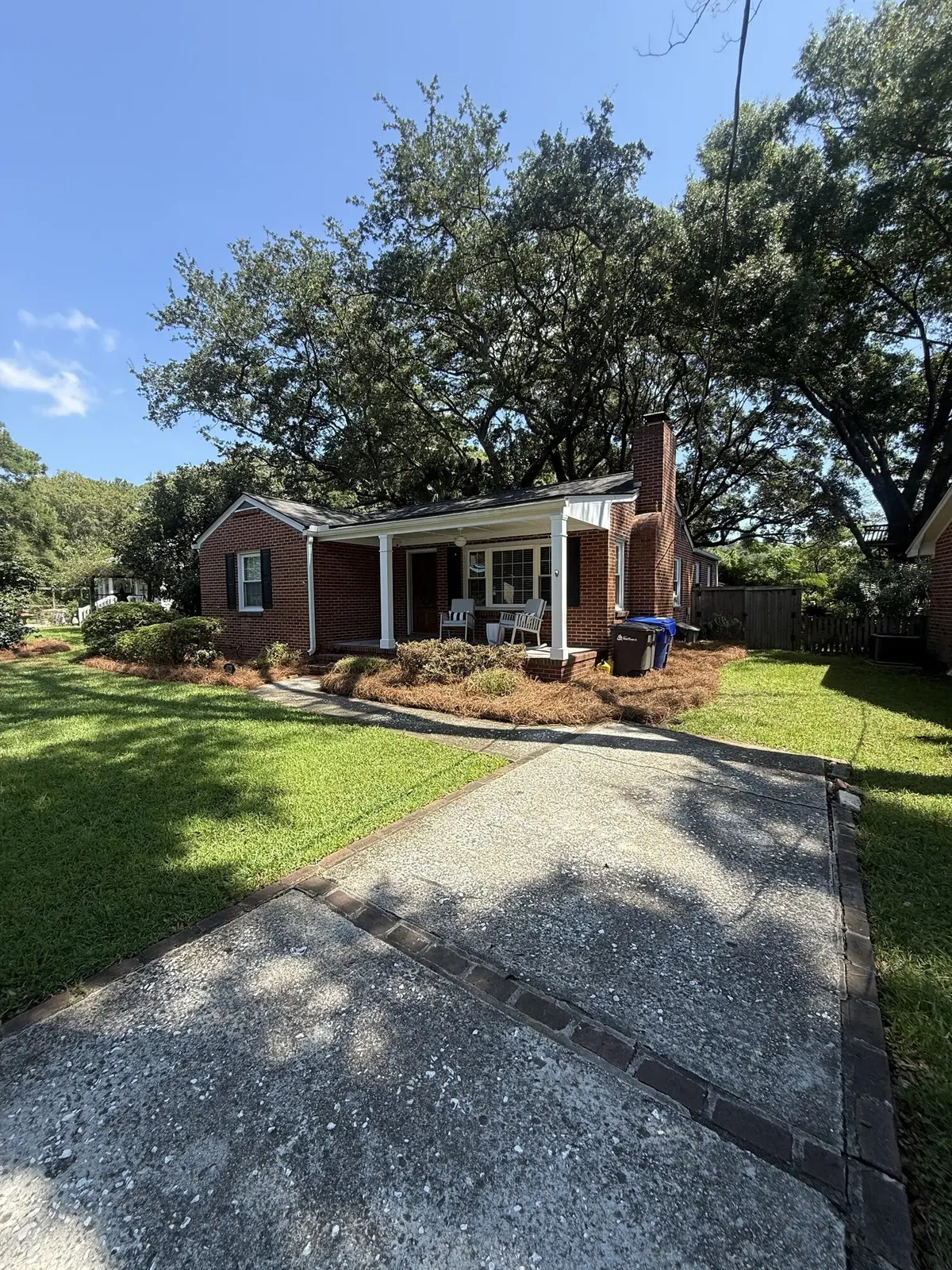 A brick cottage with fresh pine straw mulch beds and a neat lawn
