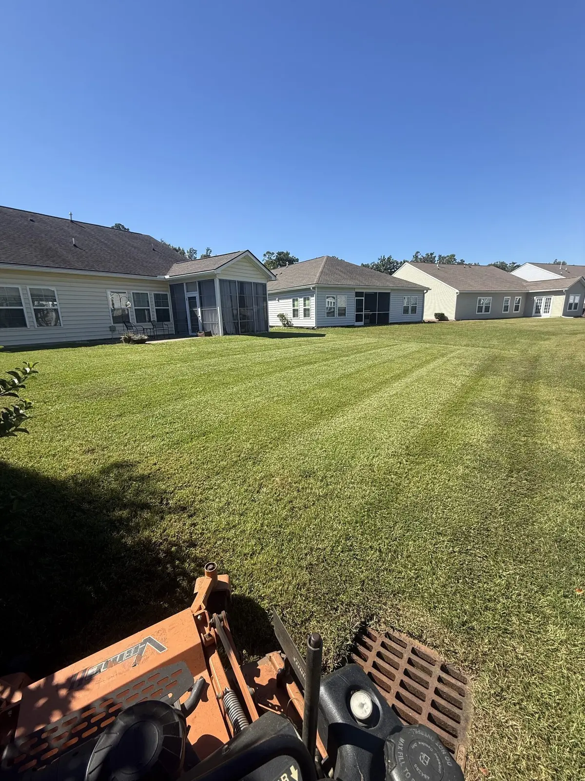 A striped lawn beside a coastal community home near a tennis court