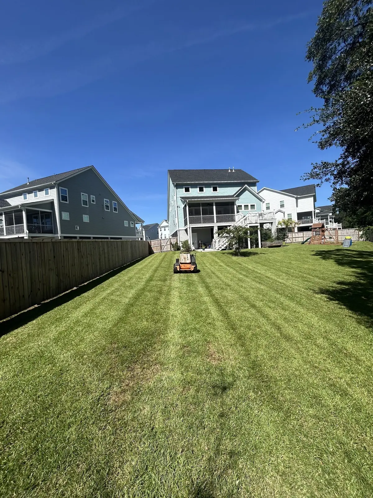 A striped backyard lawn beside a blue coastal home
