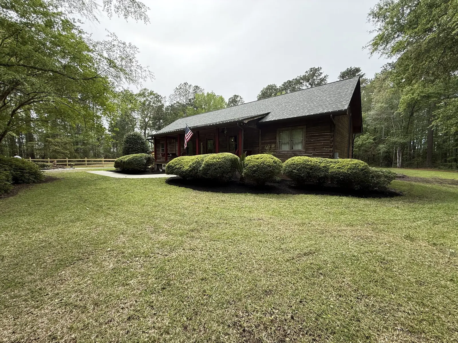 A log sided home with neatly trimmed shrubs and a mowed lawn