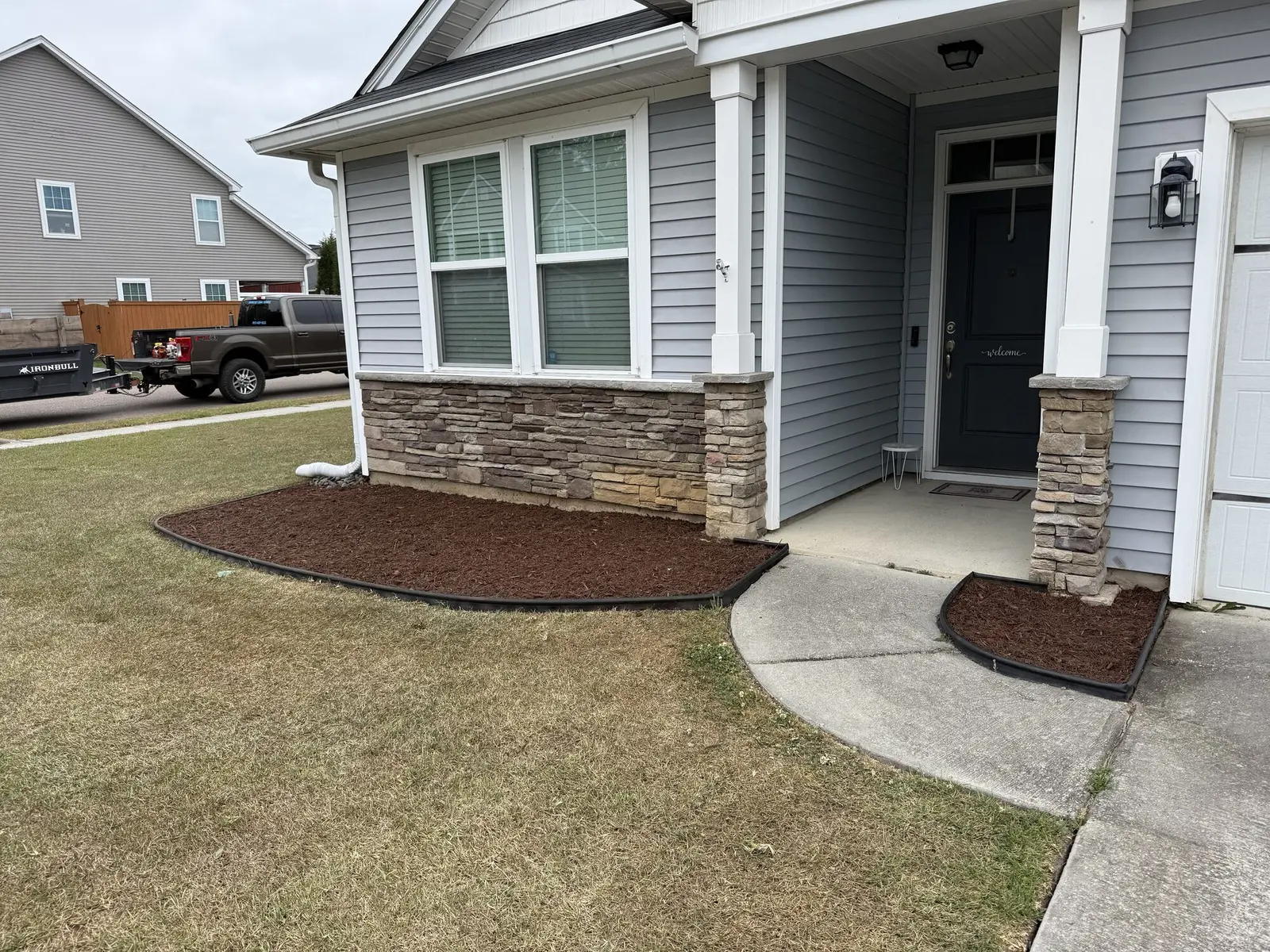 A fresh mulch bed installation at a stone accented front porch