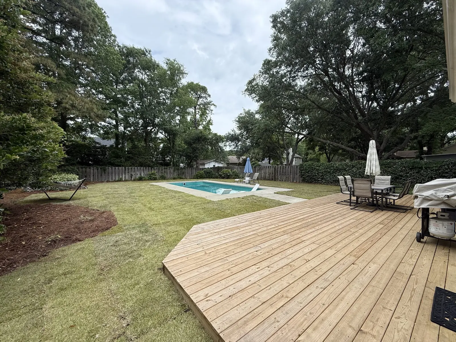 A striped lawn beside a backyard pool deck